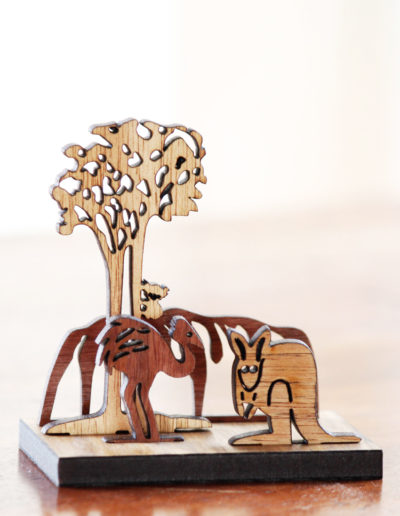 A wooden mini landscape of an Australian image with Uluru, a kangaroo, an emu and a koala in a gum tree. Four wooden images sit into a wooden base to make up the 3D landscape.