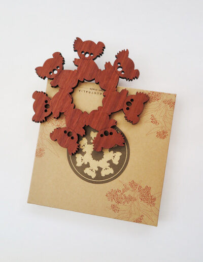 A round wooden koala design trivet in a recycled card presentation box