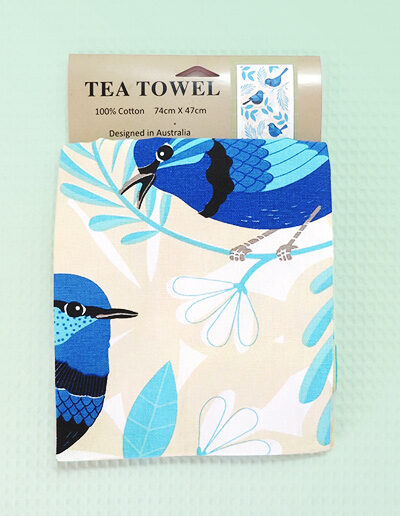 A sandy coloured cotton tea towel with Blue Wren images printed on it.