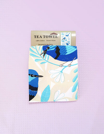 A sandy coloured cotton tea towel with Blue Wren images printed on it.