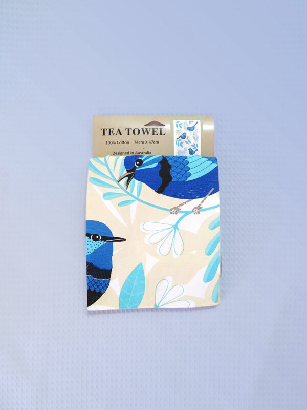 A sandy coloured cotton tea towel with Blue Wren images printed on it.