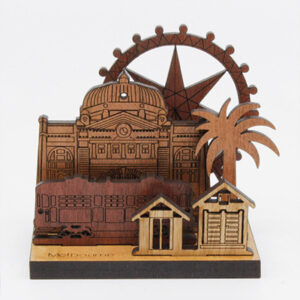 A wooden mini landscape of Melbourne with a tram, bathing houses, a palm tree, Flinders Street Station and the Melbourne Star. Five wooden images sit into a wooden base to make up the 3D landscape.