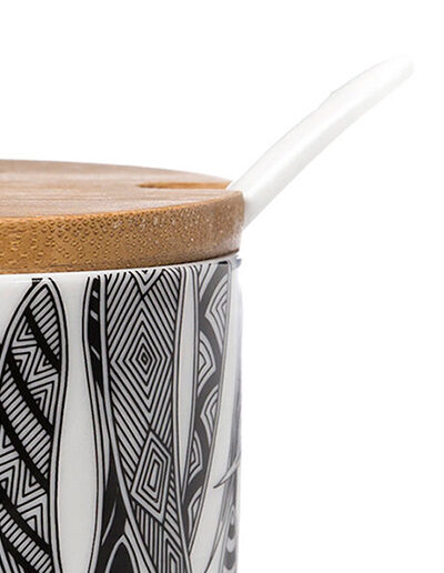 A close up detail of a Ceramic sugar bowl with a bamboo lid. The sugar bowl has artwork by Mick Harding on it. It is black and white.