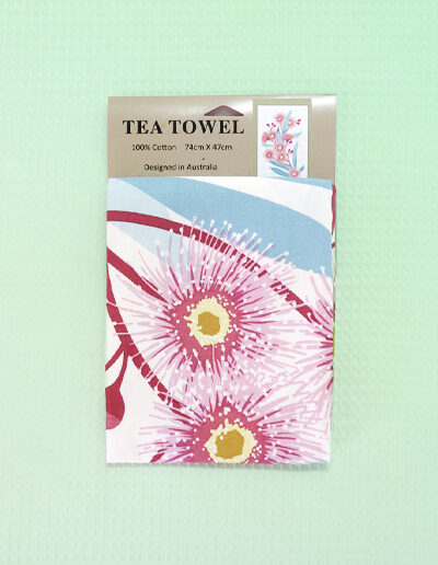 A white cotton tea towel with a large pink flowering gum print on it.