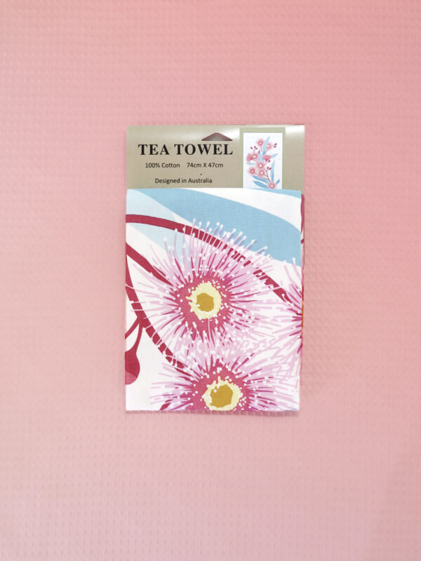A white cotton tea towel with a large pink flowering gum print on it.