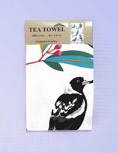 A cream cotton tea towel with Magpie images printed on it.
