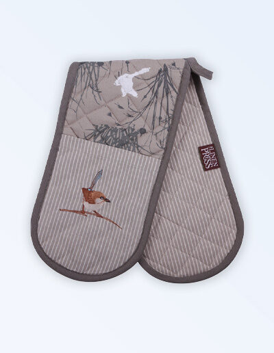 Insulated double oven mitts with an embroidered blue wren perched in grasses as the fabric design. The fabric is a natural Australian organic cotton with brown/grey trim around it and a tab to hang it.