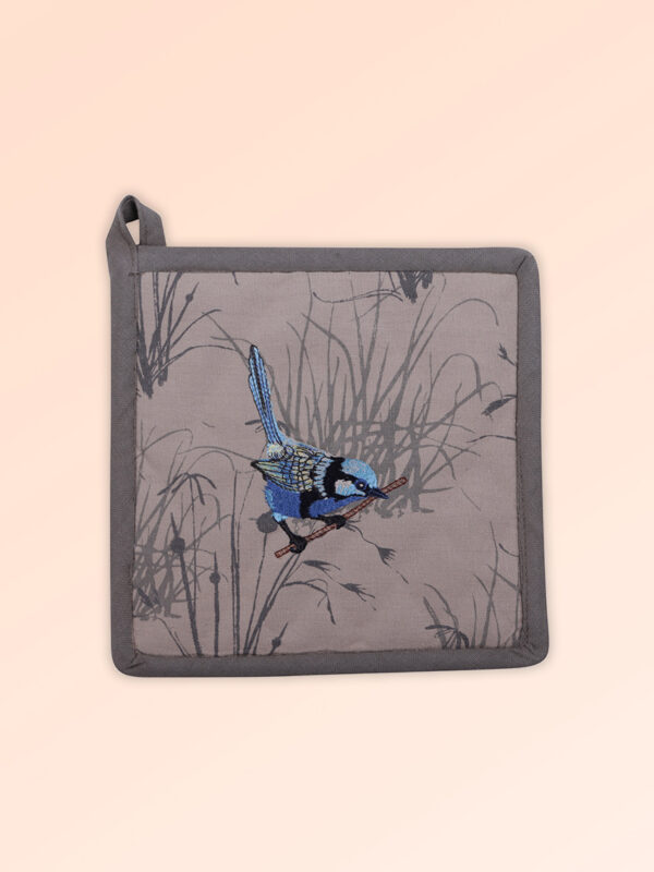 A square insulated pot holder with an embroidered blue wren perched in grasses as the fabric design. The fabric is a natural Australian organic cotton with brown/grey trim around it and a tab to hang it.