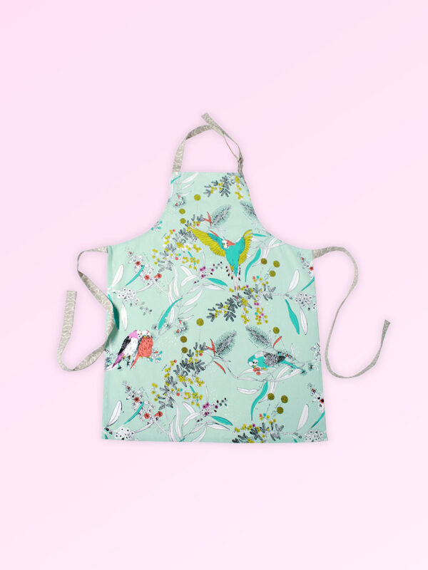 Kitchen apron with adjustable neck strap. The fabric is Australian organic cotton with an aqua background and budgerigars and small native flowers in pastel colours. The neck strap and waist straps are a soft grey.