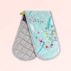 Insulated double oven mitts. The fabric is Australian organic cotton with an aqua background and budgerigars and small native flowers in pastel colours. The trim around it is soft grey with a tab for hanging.