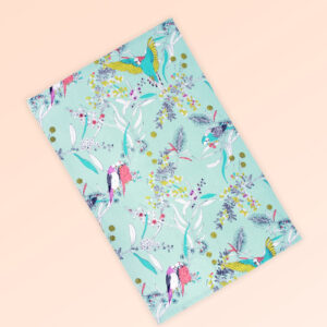 Tea towel with an aqua background and budgerigars and small native flowers in pastel colours. The fabric is a natural Australian organic cotton.
