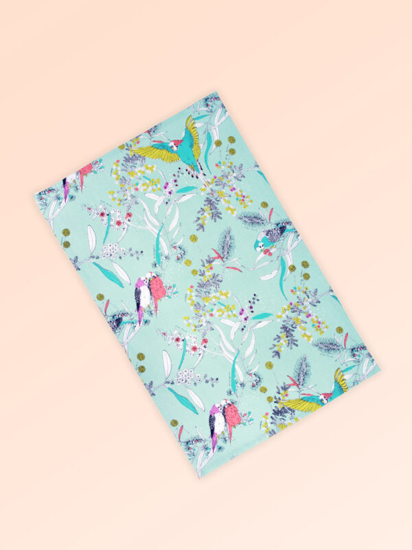 Tea towel with an aqua background and budgerigars and small native flowers in pastel colours. The fabric is a natural Australian organic cotton.