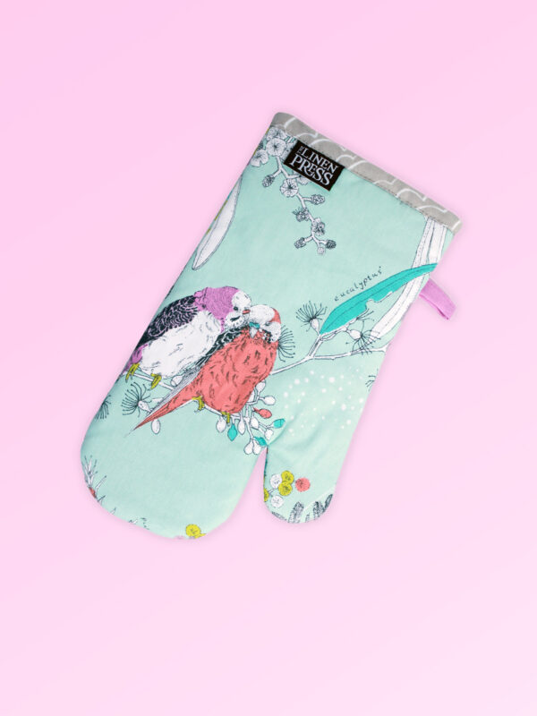 Single insulated oven mitt. The fabric is Australian organic cotton with an aqua background and budgerigars and small native flowers in pastel colours. The trim around it is soft grey with a tab for hanging.