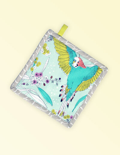 Square insulated pot holder. The fabric is Australian organic cotton with an aqua background and budgerigars and small native flowers in pastel colours. The trim around it is soft grey with a tab for hanging.