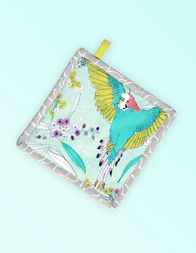 Square insulated pot holder. The fabric is Australian organic cotton with an aqua background and budgerigars and small native flowers in pastel colours. The trim around it is soft grey with a tab for hanging.