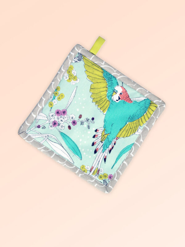 Square insulated pot holder. The fabric is Australian organic cotton with an aqua background and budgerigars and small native flowers in pastel colours. The trim around it is soft grey with a tab for hanging.