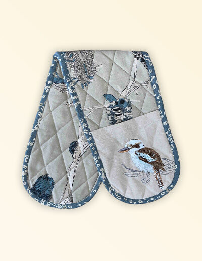 Double oven mitt, insulated. This double oven mitt is made with organic cotton featuring an embroidered Kookaburra. The oven mitt fabric is a natural cotton colour with screen printed banksia design in blue grey and beige. The edge is trimmed with a blue grey cotton fabric.