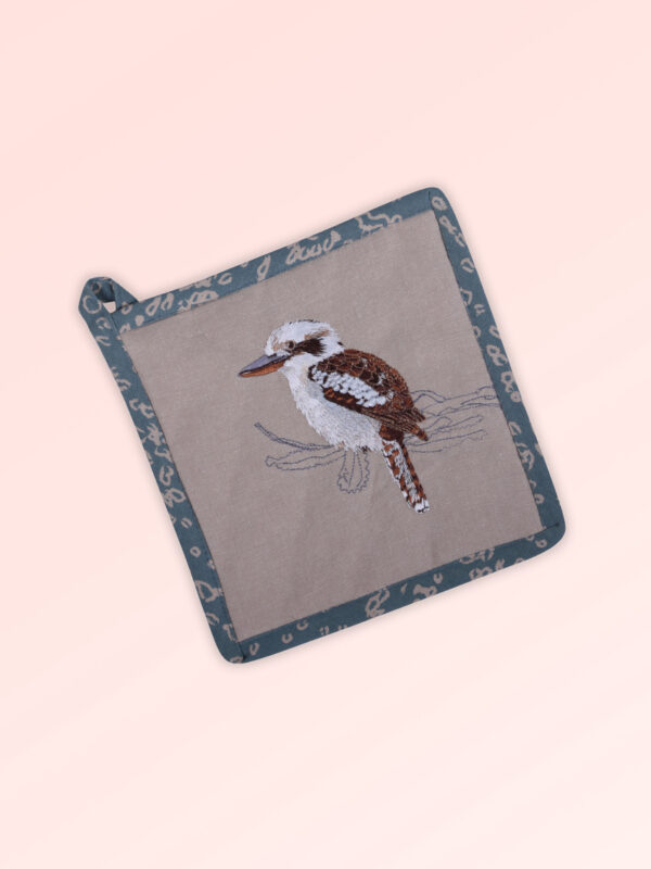 Pot holder, insulated. A square pot holder made with organic cotton featuring an embroidered Kookaburra, trimmed with a blue grey cotton fabric with a hang tie
