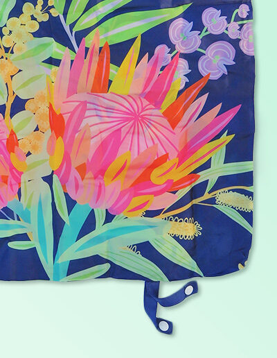 A close up of a foldable strong shopping bag printed with illustrations of Australian flora. It has a navy background. Made with polyester.