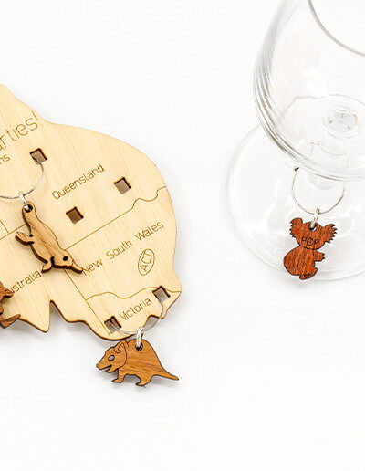 Wooden map of Australia which presents on it 6 wine glass charms of six different animals. One is attached to the map in each state.