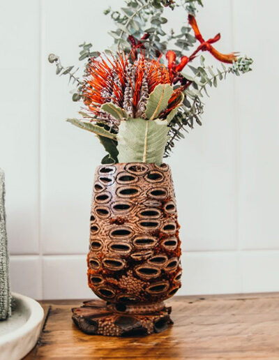 Large banksia pod tea light holder being used as a vase for flowers.
