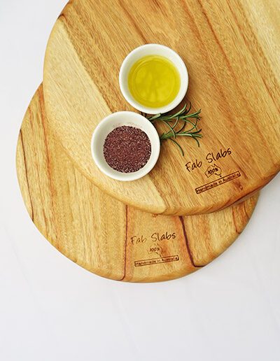 Two wooden pizza chopping boards with a dish of salt & a dish of oil