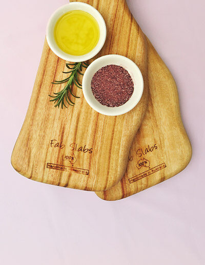 Two small wooden paddle chopping boards with a dish of salt & a dish of oil