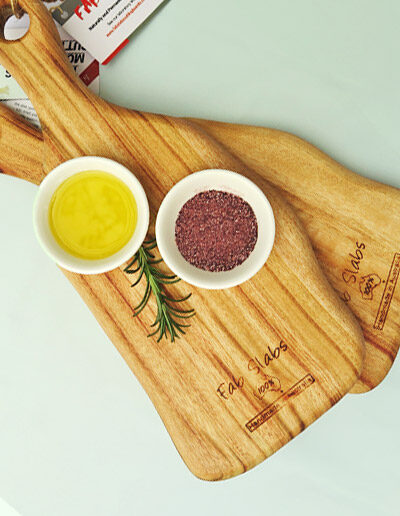 Two small wooden paddle chopping boards with a dish of salt & a dish of oil