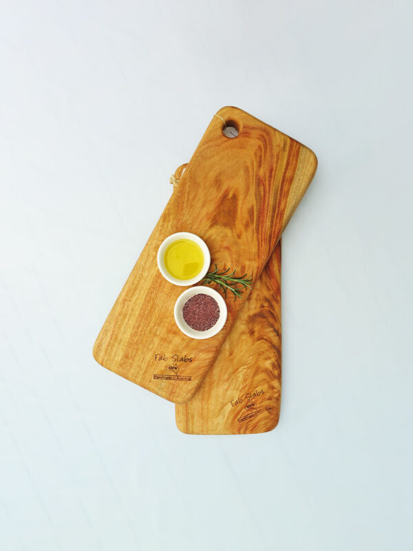 Two small wooden chopping boards with a dish of olive oil and a dish of salt