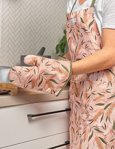 Bottlebrush Apron and single oven mitt being worn by a lady in the kitchen