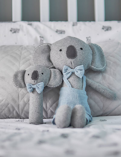 Blue Koala Cutie Plush toy and rattle sitting on a bed
