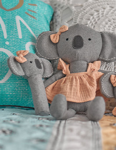 Koala Cutie pink rattle and Koala plush toy on a bed